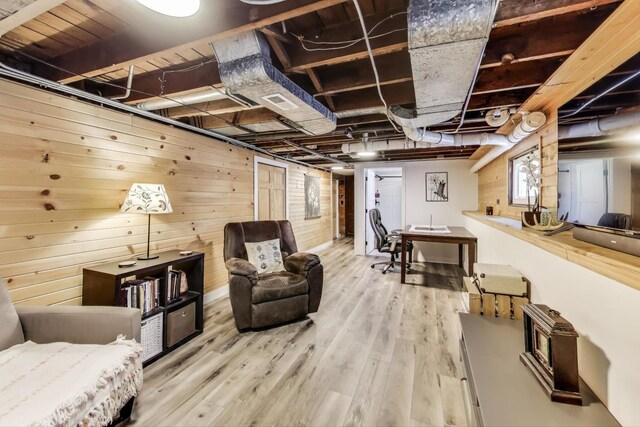 basement with wooden walls, wood finished floors, visible vents, and a healthy amount of sunlight