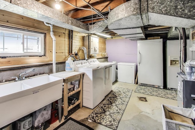 laundry area featuring washing machine and clothes dryer, wood walls, a sink, and laundry area