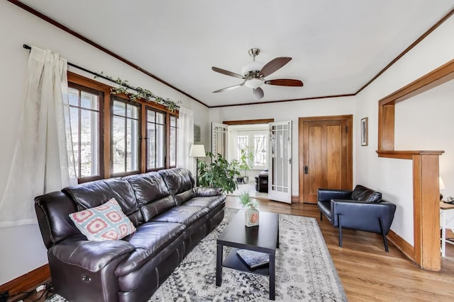 living area featuring ceiling fan, baseboards, ornamental molding, and wood finished floors