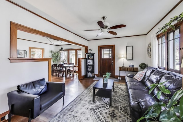 living area featuring ornamental molding, baseboards, wood finished floors, and ceiling fan
