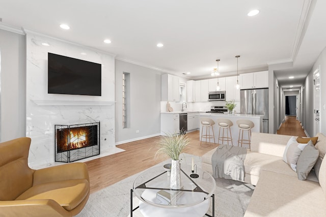 living room featuring crown molding, recessed lighting, a fireplace, and light wood finished floors