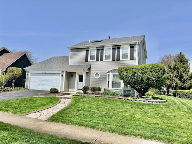 view of front of house with asphalt driveway, a garage, a front lawn, and a shingled roof