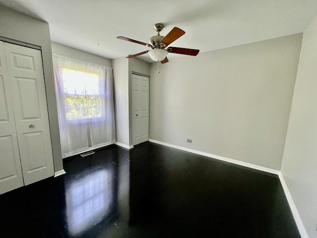 unfurnished bedroom with baseboards, ceiling fan, and dark wood-style flooring