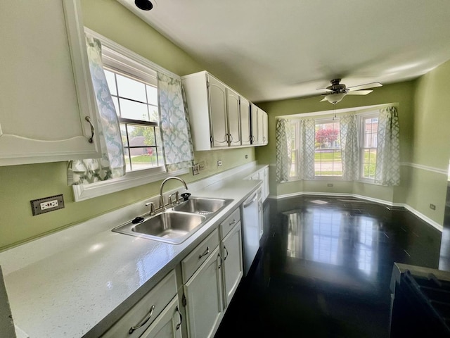 kitchen with a sink, healthy amount of natural light, dishwashing machine, and white cabinetry