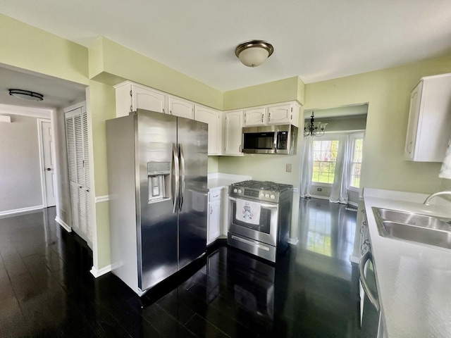 kitchen with appliances with stainless steel finishes, a sink, white cabinets, and dark wood-type flooring