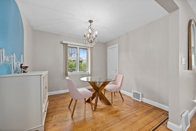 dining space featuring a chandelier, light wood-type flooring, and baseboards
