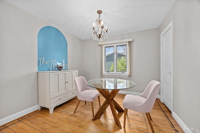 dining area with light wood-style flooring, a chandelier, and baseboards