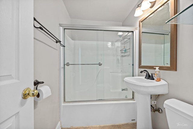 bathroom with toilet and shower / bath combination with glass door