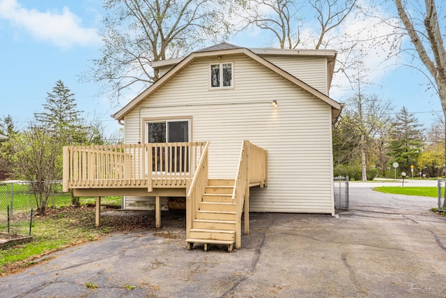 back of property featuring a wooden deck, fence, and stairs