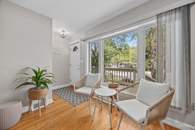 living area with wood finished floors, baseboards, and a chandelier
