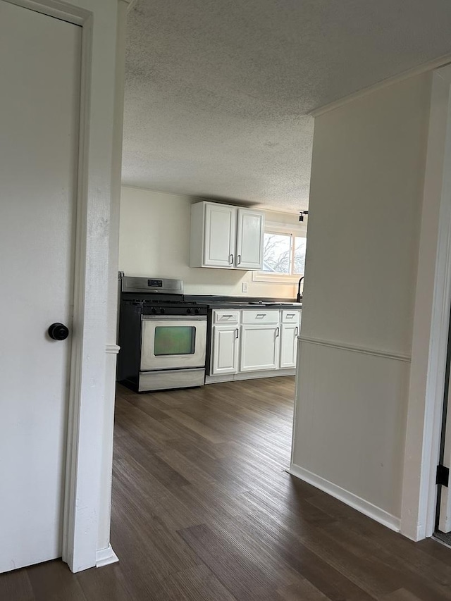 kitchen featuring white cabinets, dark wood-style floors, dark countertops, stainless steel gas range, and a textured ceiling