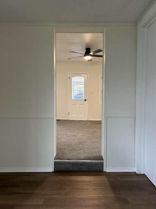 hallway featuring dark wood-style flooring, ornamental molding, and baseboards