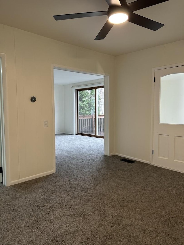 unfurnished room with ceiling fan, baseboards, dark colored carpet, and visible vents