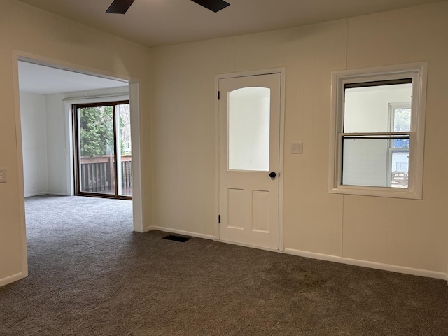 entryway with visible vents, a ceiling fan, baseboards, and dark carpet