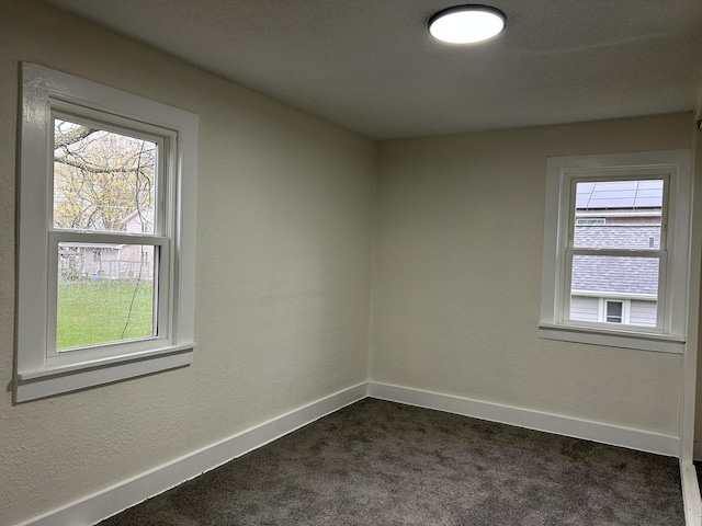 empty room with dark carpet and baseboards