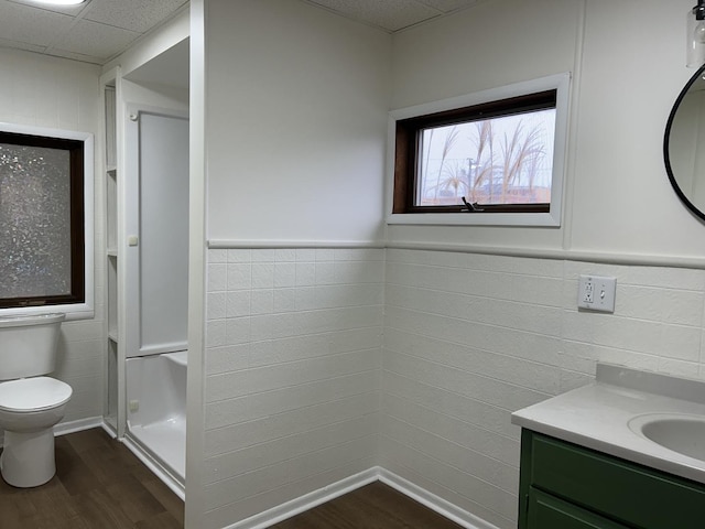 bathroom featuring a wainscoted wall, a drop ceiling, toilet, wood finished floors, and vanity
