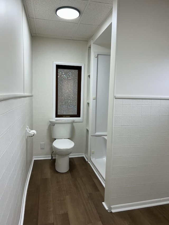 bathroom featuring wood finished floors, toilet, tile walls, and wainscoting