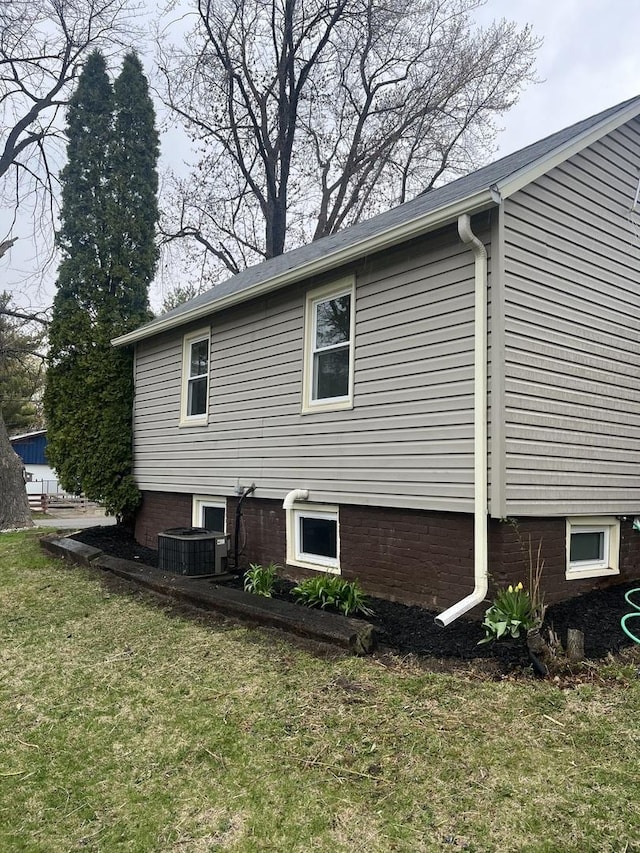 view of side of home with central air condition unit and a lawn