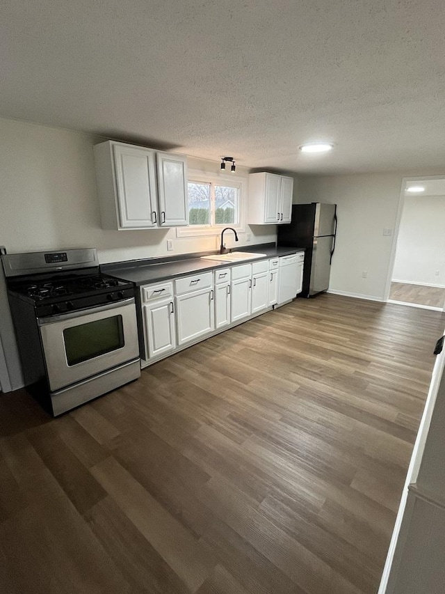 kitchen with stainless steel gas range, wood finished floors, a sink, and freestanding refrigerator
