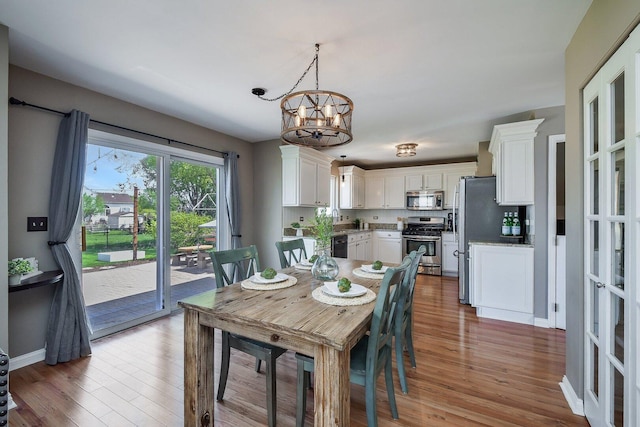 dining space with wood finished floors, a chandelier, and baseboards