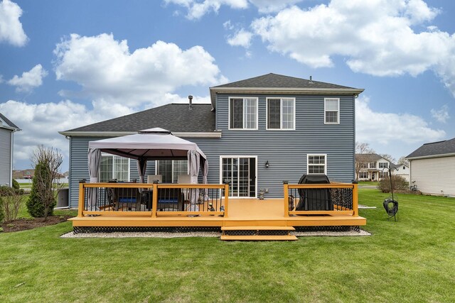 rear view of property with a wooden deck, a gazebo, a yard, and a shingled roof