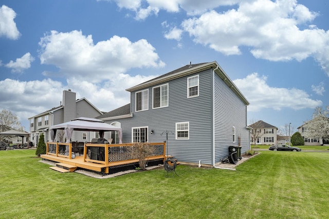 rear view of house with a lawn, a wooden deck, and a gazebo