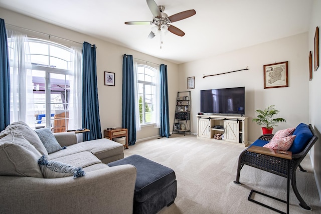 living area with light carpet, a ceiling fan, and baseboards