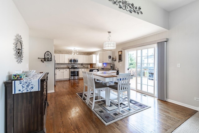 dining area with dark wood-type flooring, a chandelier, and baseboards