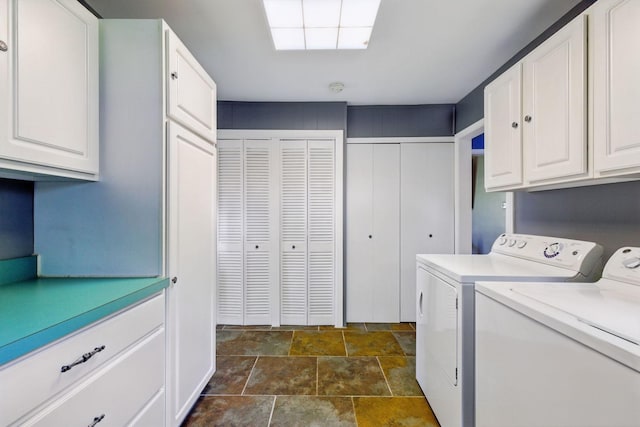 washroom featuring washer and dryer, cabinet space, and stone finish flooring