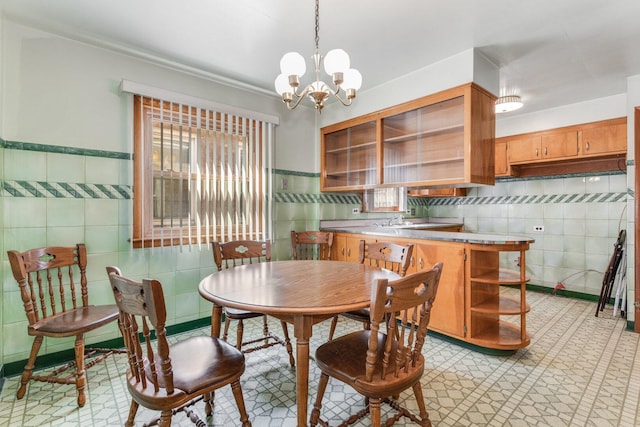 dining room featuring wainscoting, an inviting chandelier, and tile walls