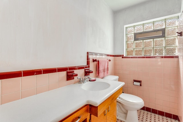 bathroom featuring tile patterned floors, a wainscoted wall, toilet, tile walls, and vanity