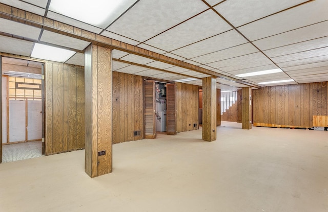 basement with wood walls and a paneled ceiling