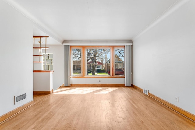 unfurnished room with wood finished floors, visible vents, and baseboards