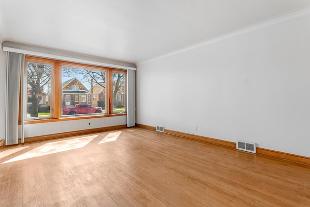 spare room featuring wood finished floors, visible vents, and baseboards