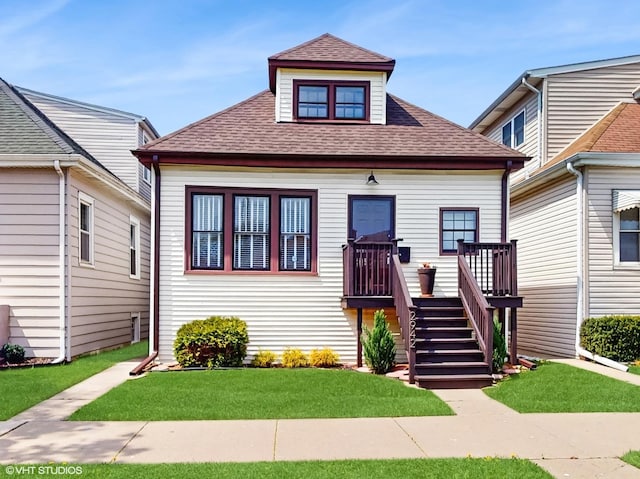 bungalow-style home with a shingled roof and a front lawn