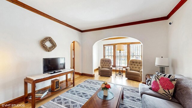 living area featuring crown molding, arched walkways, baseboards, and wood finished floors
