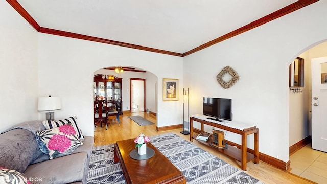 living area featuring arched walkways, ornamental molding, baseboards, and light wood-type flooring