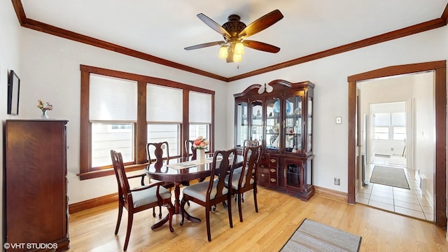 dining room featuring crown molding, baseboards, ceiling fan, and light wood finished floors