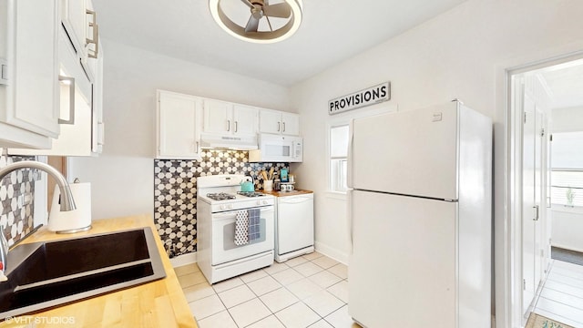 kitchen featuring tasteful backsplash, a sink, white cabinets, under cabinet range hood, and white appliances