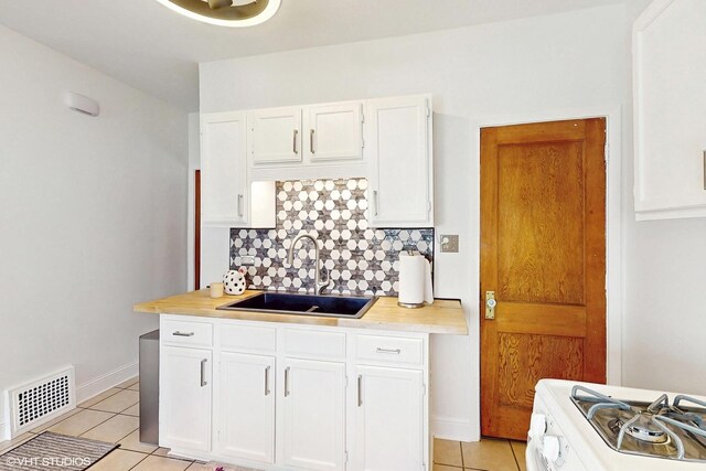 kitchen with a sink, white gas range, light tile patterned flooring, and visible vents