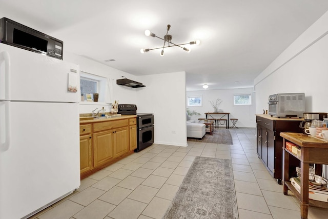 kitchen with a sink, light tile patterned flooring, double oven range, freestanding refrigerator, and light countertops