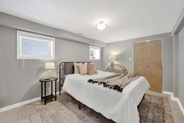 bedroom featuring visible vents, baseboards, a closet, and light tile patterned floors