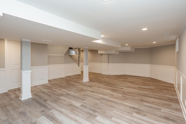 finished below grade area featuring stairway, recessed lighting, wainscoting, and light wood-type flooring