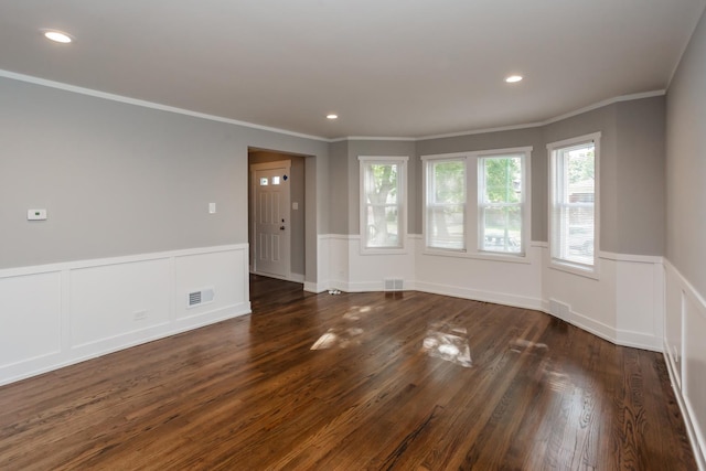 unfurnished room featuring visible vents, crown molding, dark wood-style floors, and wainscoting