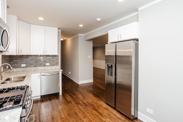 kitchen with tasteful backsplash, a sink, appliances with stainless steel finishes, dark wood-style flooring, and light stone countertops