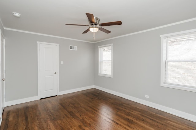 empty room with visible vents, dark wood-type flooring, ceiling fan, and crown molding