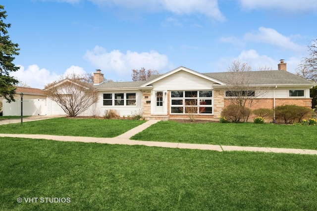 back of property featuring a chimney, a garage, and a lawn