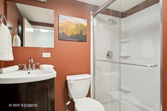 bathroom with a stall shower, toilet, and vanity