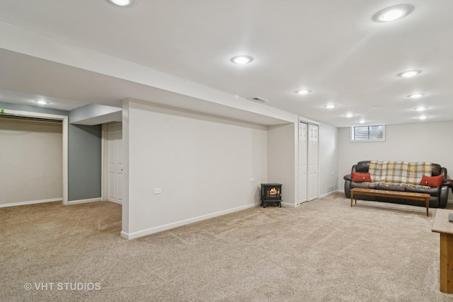 interior space featuring visible vents, recessed lighting, carpet, baseboards, and a wood stove