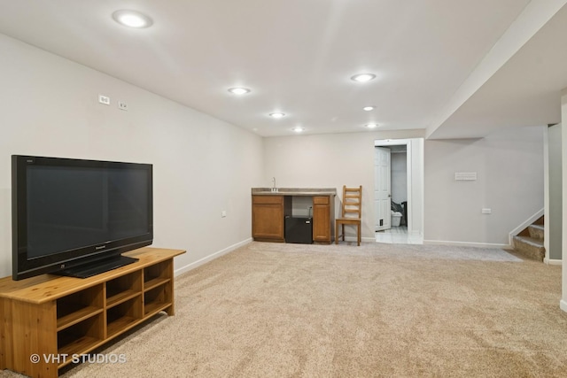unfurnished living room with baseboards, recessed lighting, light carpet, wet bar, and stairs